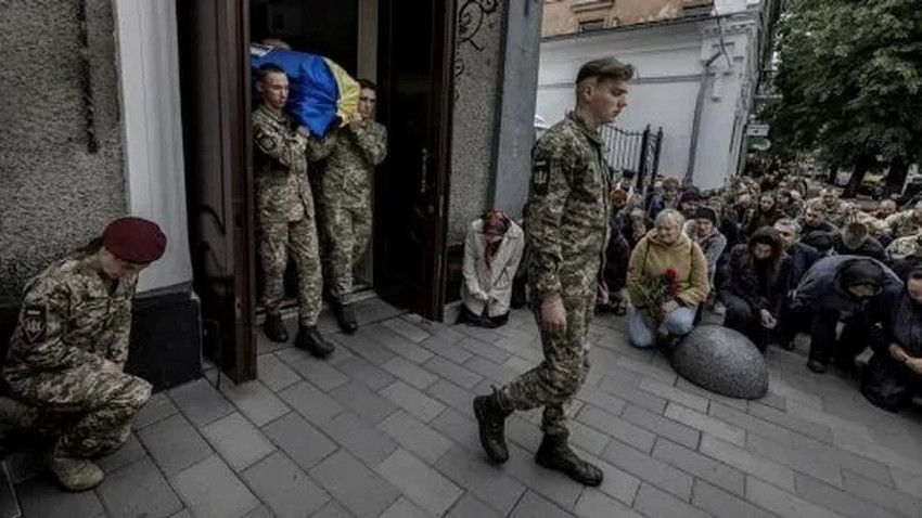 Foto: Savaşta hayatını kaybeden Ukraynalı bir askerin cenazesi dini tören sonrasında kiliseden çıkarılıyor. Törene katılanlar onu diz çökerek ve huşu içinde uğurluyor.